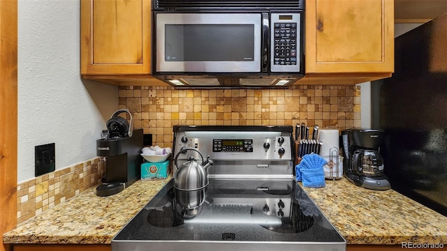 kitchen with tasteful backsplash, appliances with stainless steel finishes, and light stone countertops