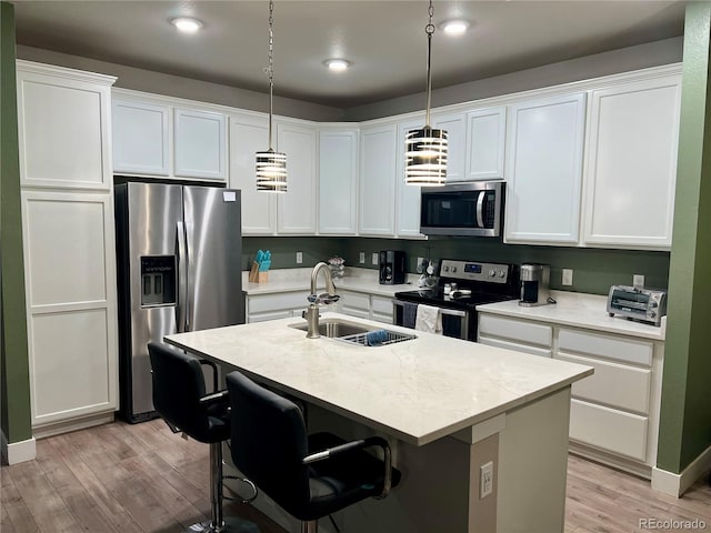 15354 W 64th Ln Unit 108, Arvada, CO 80007 - kitchen with stainless steel appliances, light wood finished floors, light countertops, an island with sink, and recessed lighting