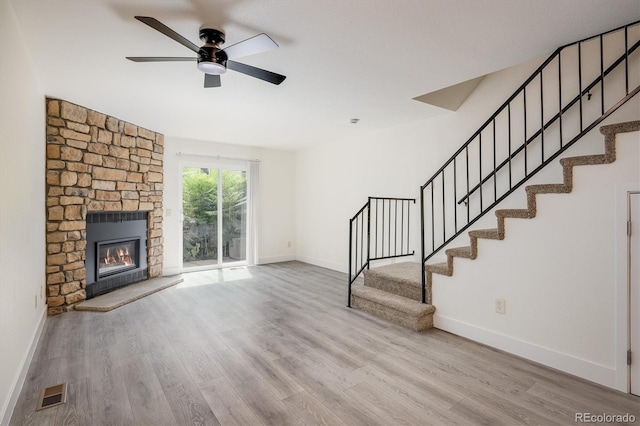 2933 W 81st Ave Unit F, Westminster, CO 80031 - unfurnished living room with wood finished floors, ceiling fan, stairs, and a stone fireplace