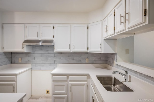 2933 W 81st Ave Unit F, Westminster, CO 80031 - kitchen with under cabinet range hood, white cabinetry, light countertops, and backsplash