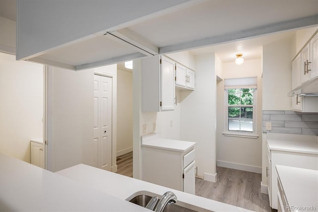 2933 W 81st Ave Unit F, Westminster, CO 80031 - kitchen with light wood-style floors, light countertops, tasteful backsplash, and white cabinetry