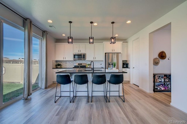 kitchen with dark countertops, visible vents, a kitchen bar, appliances with stainless steel finishes, and a sink