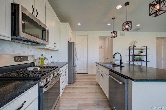 kitchen featuring a center island with sink, a sink, stainless steel appliances, white cabinets, and decorative backsplash