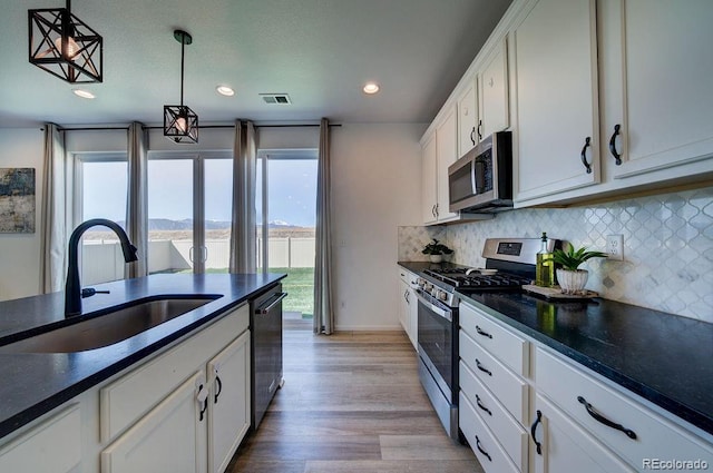 kitchen with visible vents, a sink, tasteful backsplash, dark countertops, and stainless steel appliances