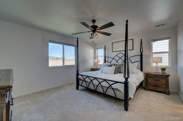 bedroom with baseboards, light colored carpet, visible vents, and a textured ceiling