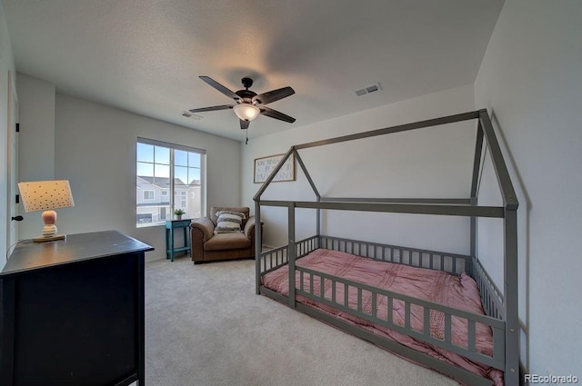 bedroom featuring a textured ceiling, carpet flooring, visible vents, and ceiling fan