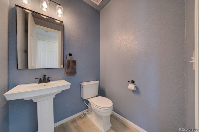 bathroom featuring a sink, baseboards, toilet, and wood finished floors