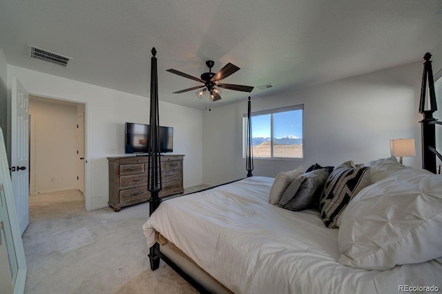 bedroom with visible vents, light colored carpet, a textured ceiling, and ceiling fan