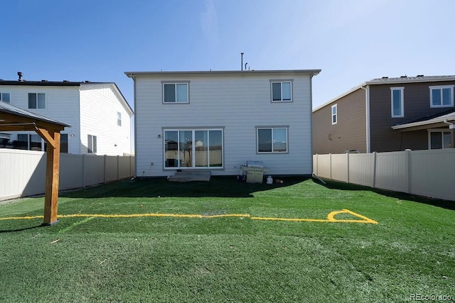 rear view of house featuring a lawn and a fenced backyard