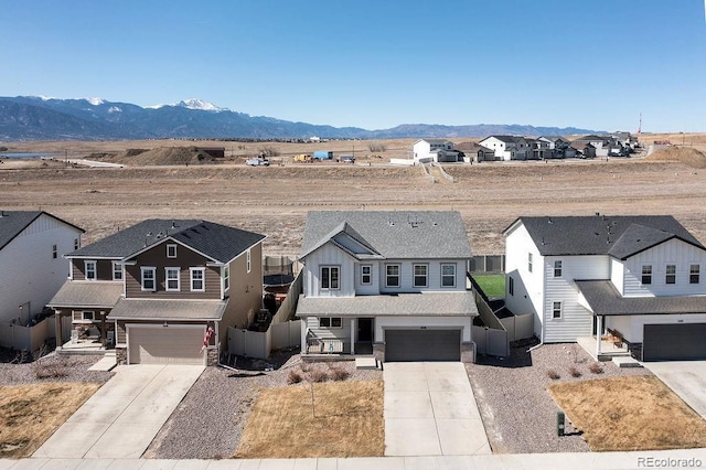 view of front of house featuring a mountain view, an attached garage, a residential view, and driveway