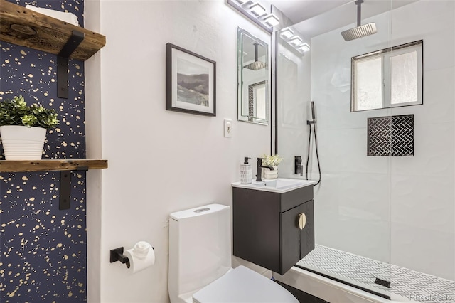 bathroom featuring a tile shower, vanity, and toilet