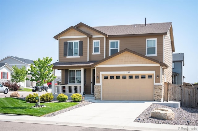 craftsman-style home with concrete driveway, a porch, fence, and stone siding
