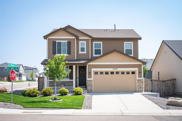 craftsman inspired home with covered porch, stone siding, fence, concrete driveway, and a front yard