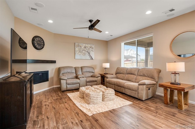 living area with a ceiling fan, baseboards, visible vents, and wood finished floors