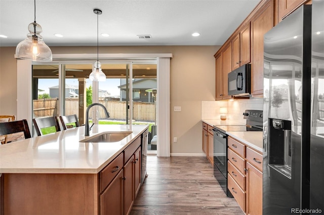 kitchen featuring a sink, brown cabinetry, black appliances, dark wood-style flooring, and decorative backsplash