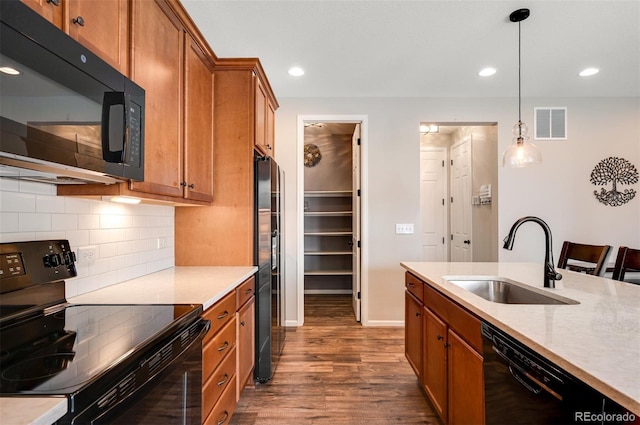 kitchen featuring a sink, brown cabinetry, black appliances, visible vents, and dark wood-type flooring