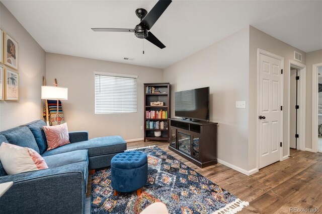 living room featuring visible vents, wood finished floors, baseboards, and ceiling fan