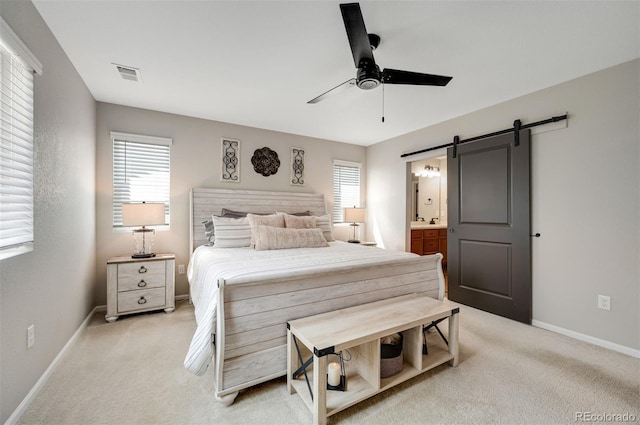 bedroom featuring light carpet, a barn door, baseboards, and visible vents