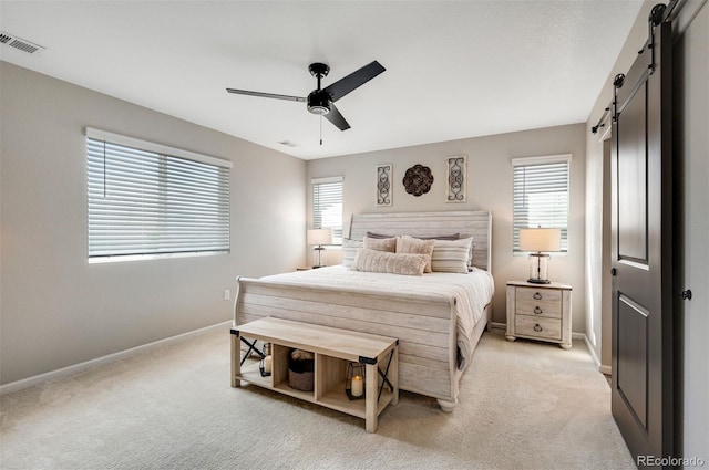 bedroom featuring multiple windows, a barn door, visible vents, and light colored carpet