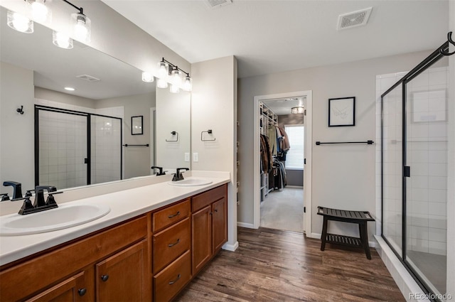full bath featuring a shower stall, visible vents, a sink, and double vanity