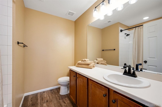 bathroom featuring toilet, baseboards, visible vents, and wood finished floors