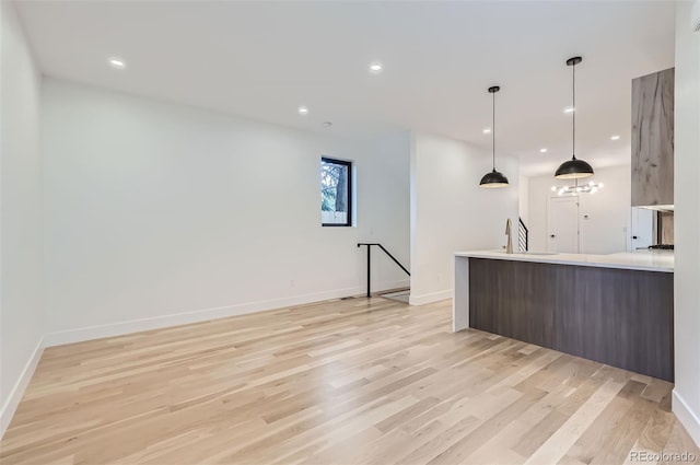 kitchen with decorative light fixtures, light hardwood / wood-style flooring, and sink