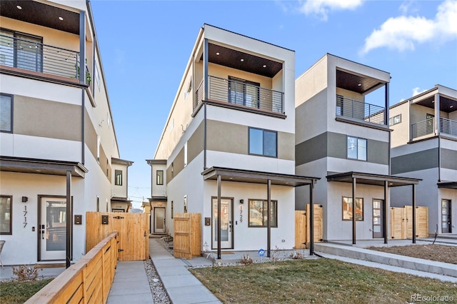 contemporary home with a gate, fence, and stucco siding