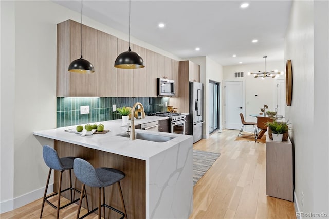 kitchen featuring a breakfast bar area, a sink, backsplash, high end appliances, and modern cabinets