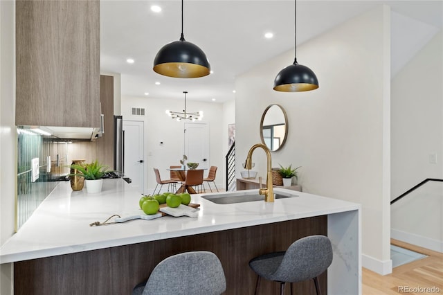 kitchen with visible vents, modern cabinets, a breakfast bar, a peninsula, and a sink