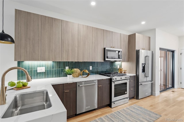 kitchen featuring stainless steel appliances, modern cabinets, a sink, and light wood-style flooring