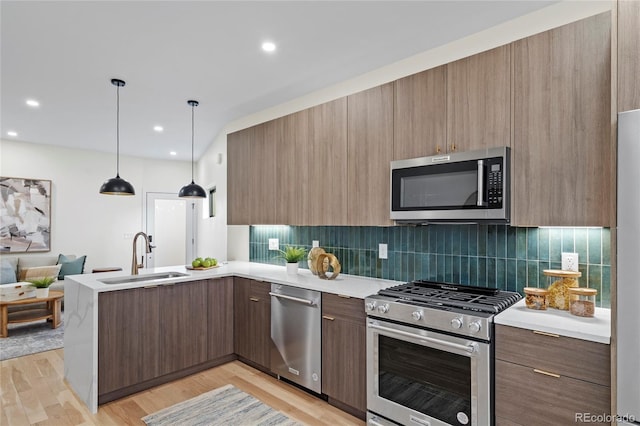 kitchen featuring stainless steel appliances, a sink, a peninsula, and modern cabinets