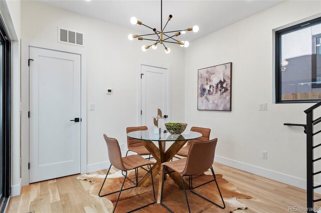 dining area with light wood-type flooring, visible vents, and baseboards