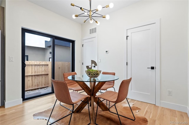 dining area with visible vents, a notable chandelier, light wood-style flooring, and baseboards