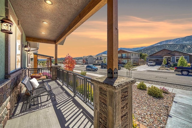 balcony at dusk with a mountain view and covered porch