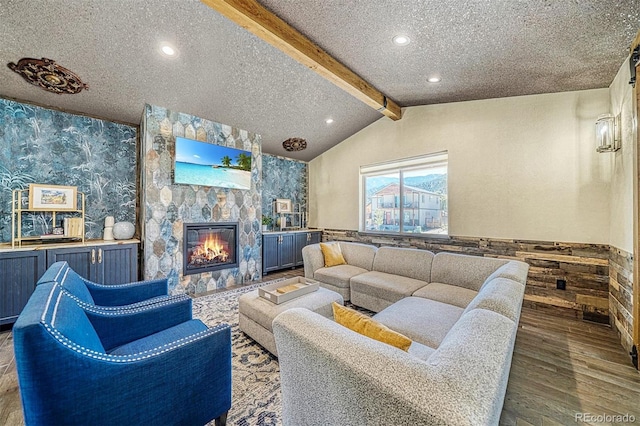 living room with hardwood / wood-style floors, a fireplace, vaulted ceiling with beams, and a textured ceiling