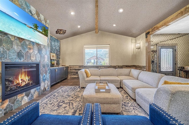 living room with a textured ceiling, a fireplace, vaulted ceiling with beams, and dark wood-type flooring