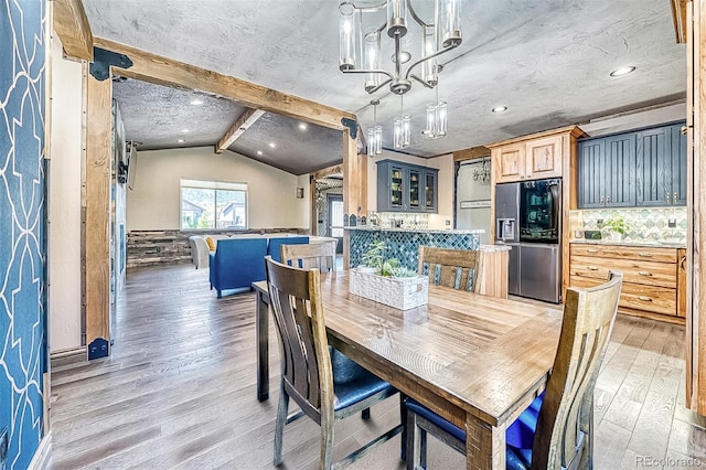 dining room featuring a chandelier, hardwood / wood-style floors, and vaulted ceiling with beams