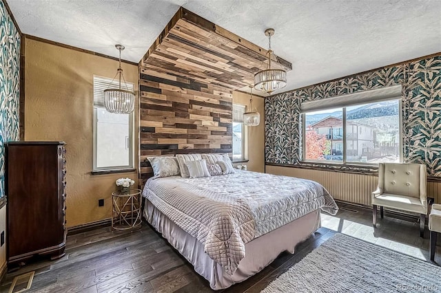 bedroom with hardwood / wood-style flooring, a textured ceiling, and a chandelier