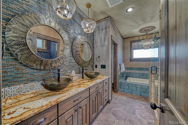 bathroom with tile patterned flooring, tiled bath, a chandelier, a textured ceiling, and vanity