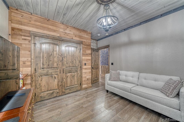 living room with hardwood / wood-style flooring, wood ceiling, wooden walls, and a chandelier