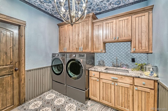 clothes washing area featuring independent washer and dryer, sink, cabinets, and an inviting chandelier