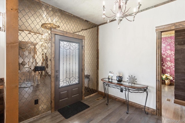 entryway featuring baseboards, an inviting chandelier, and wood finished floors