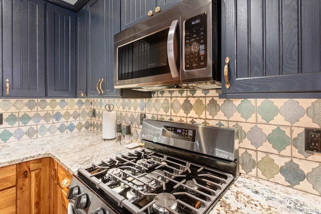 kitchen featuring appliances with stainless steel finishes, decorative backsplash, brown cabinets, and light stone countertops