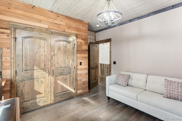 living room featuring wood ceiling, a notable chandelier, wooden walls, and wood finished floors