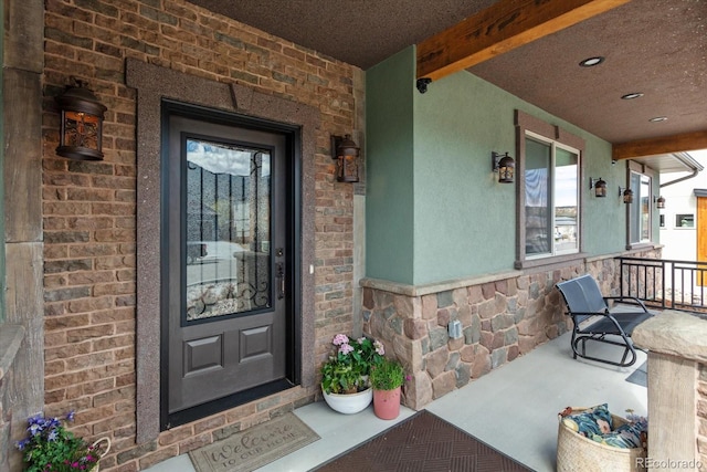 property entrance with a porch, brick siding, and stone siding