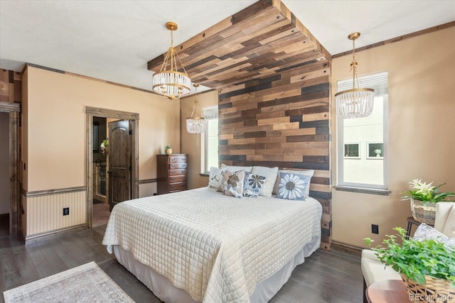 bedroom featuring an inviting chandelier, baseboards, wood walls, and wood finished floors