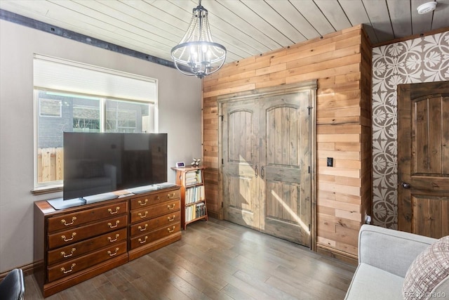 living area with a chandelier, wooden walls, wooden ceiling, and dark wood-style floors
