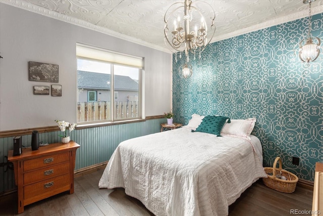 bedroom featuring a chandelier, a wainscoted wall, hardwood / wood-style floors, wallpapered walls, and ornamental molding