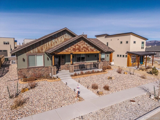 craftsman-style home featuring covered porch and stone siding