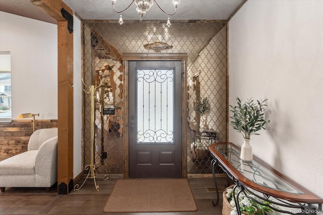 foyer featuring baseboards, wood finished floors, and a chandelier